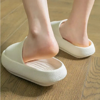 A close-up of feet slipping into CozySteps Unisex EVA Beach & Bathroom Flip-Flops by CozySteps.uk, US sizes 6–12. These beige flip-flops feature textured, non-slip soles and offer cushioned comfort on wooden floors.